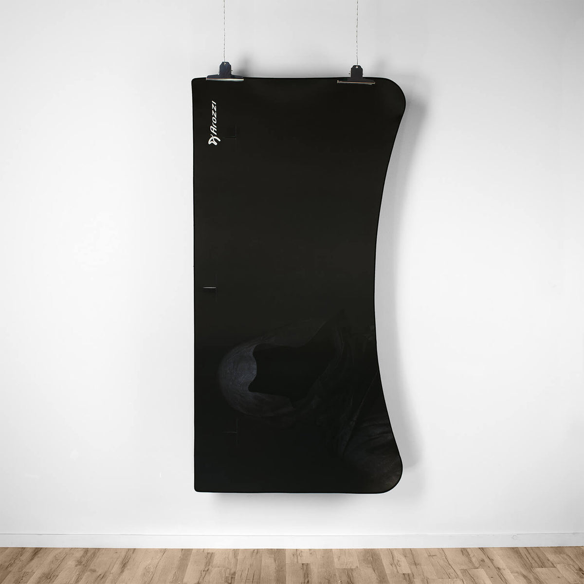 Curved black board above Arozzi Europe Arena Mousepad on light wood floor against a white wall.