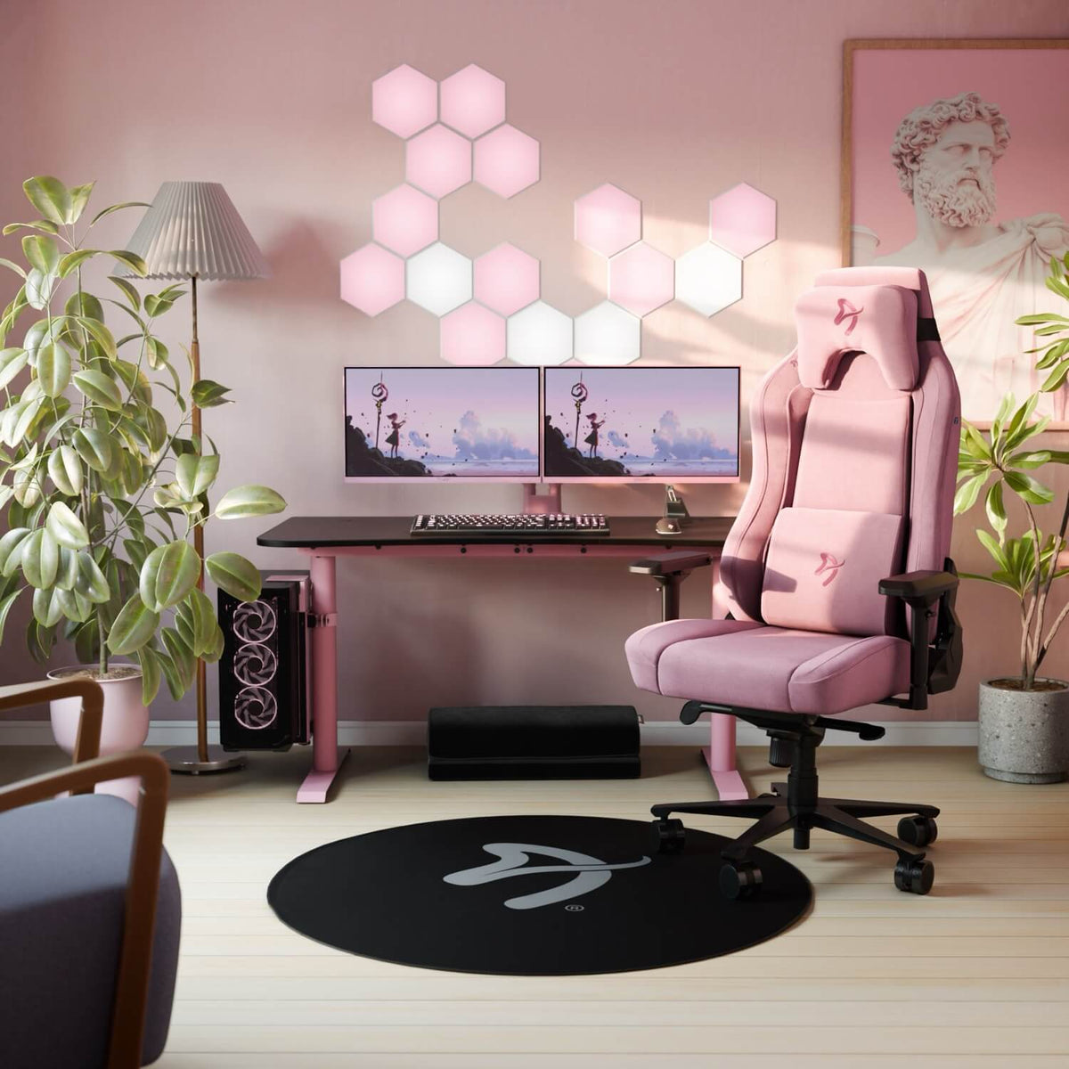 Pink gaming setup with Arozzi Arena desk, LED wall lights, dual monitors, and plants.