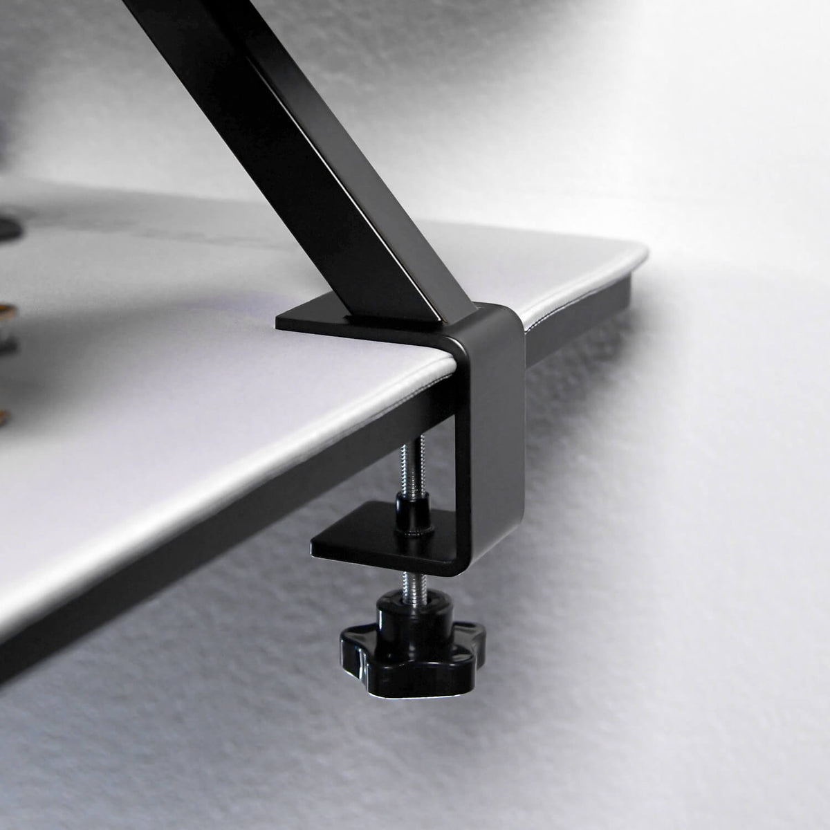 Arozzi Europe’s Desk Riser - Large clamps to a white desk’s edge against the wall.