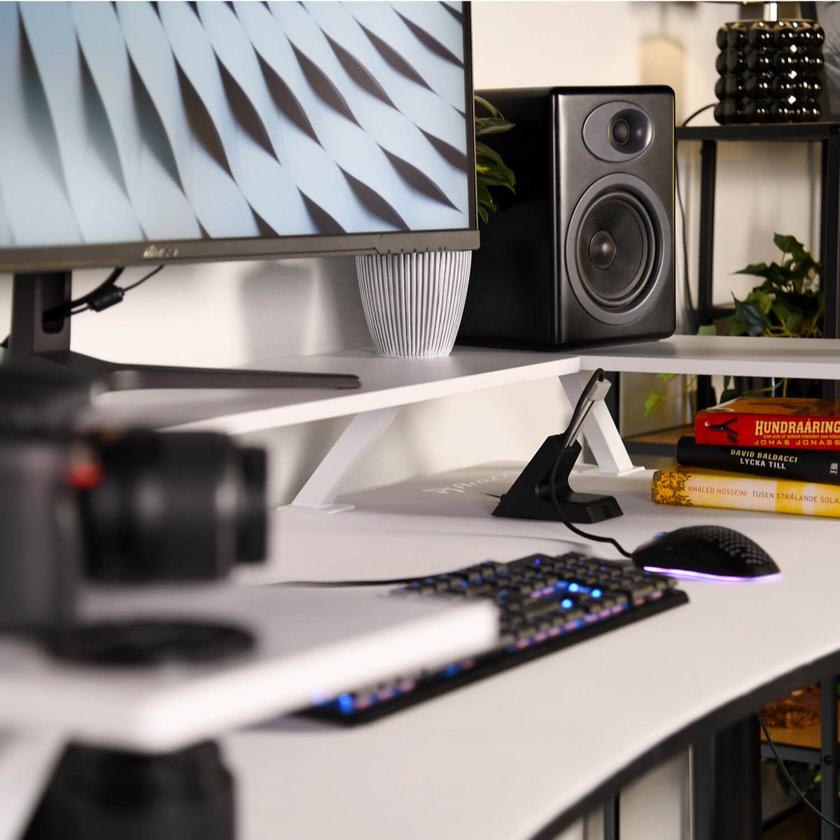 Curved monitor on Desk Riser - Large by Arozzi Europe with keyboard, mouse, books, camera, plants.